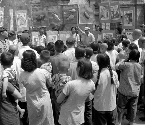 　　1953年6月，北京前炒面胡同爱国卫生运动委员会分会宣传队正在向群众讲解蚊、蝇怎样传染疾病。图源：毛松友|新华社