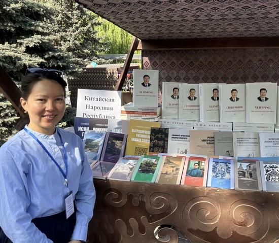 这是艾依米拉在吉尔吉斯斯坦当地书展上的留影，展出图书均为中国书籍的对外译文版本。