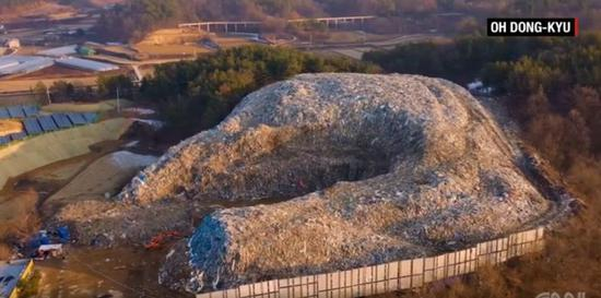 （图为义城郡的巨大垃圾山，注意与左下角的房屋作对比 图源：CNN）