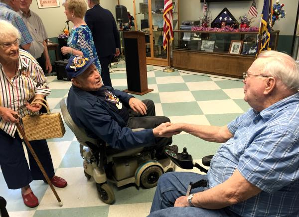 　　当地时间2015年8月1日，美国路易斯安那州门罗市的二战老兵和家人齐聚“老兵之家”，纪念二战结束70周年。图为坐在轮椅上的谢尔曼（左）与老兵握手互致问候。 视觉中国 资料