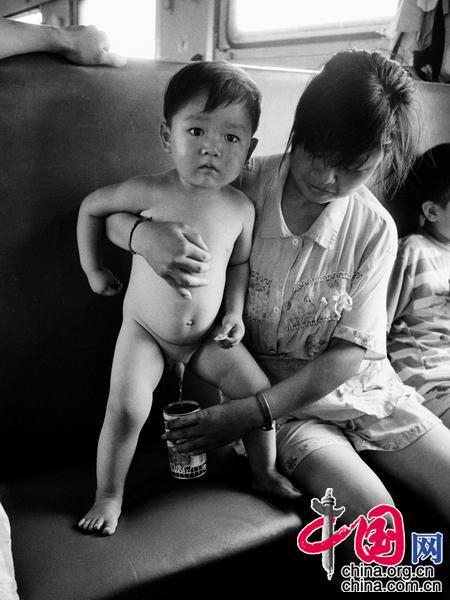 1992年，南宁——北京。年轻的妈妈想出了用八宝粥的铁罐来当作“临时厕所”，以解决儿子的内急。王福春摄影