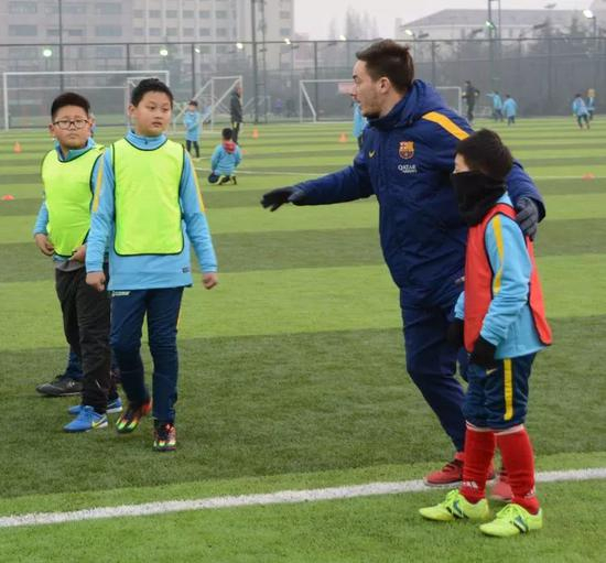 　　巴萨俱乐部青训教练阿尔贝·莫拉塔利亚（右二）在中国·巴萨青岛黄海足球学校为小球员讲解技术要领。新华社记者张旭东摄