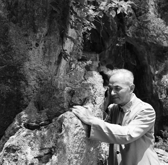 1957年6月，李四光在杭州飞来峰用放大镜察看石灰岩中的有孔虫化石。 新华社发（资料照片）