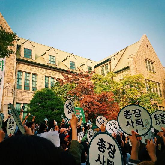 　　△ 2016 年 10 月 19 日，梨花女子大学教职人员和学生们共同参加了“要求校长为‘崔顺实女儿舞弊入学’事件负责、卸任校长”的示威游行活动。这也是事件爆发后最大规模的示威游行活动。当天下午，梨花女子大学时任校长引咎辞职。摄影 | 侯珺
