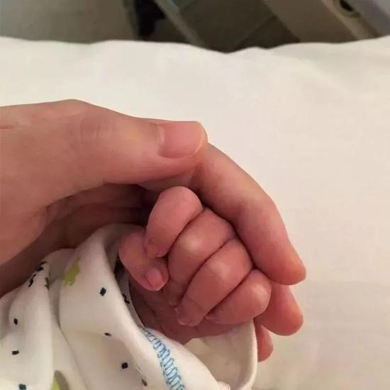 2017年5月，张萌握着刚出生的欣欣的手。受访者供图