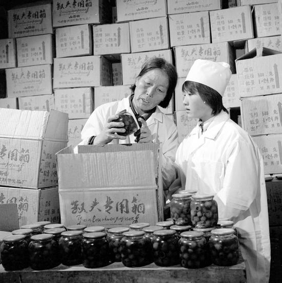 申纪兰带领群众脱贫致富，1986年9月与县供销社联合办起一座罐头厂，投产后的第一个月就生产红果、梨罐头5万多瓶。这是申纪兰（左）和工人一起检查罐头质量（资料照片）。新华社发