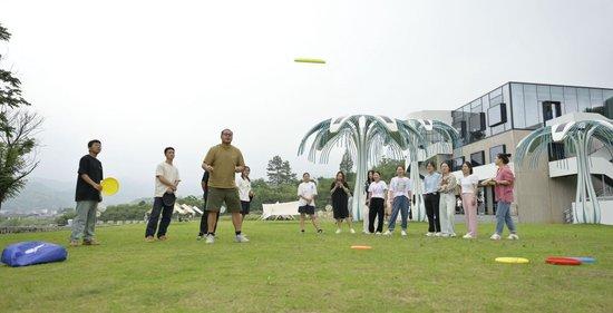在浙江省湖州市安吉县天荒坪镇余村乡村图书馆前，年轻人在草坪上玩飞盘（2023年6月5日摄）。新华社记者 才扬 摄