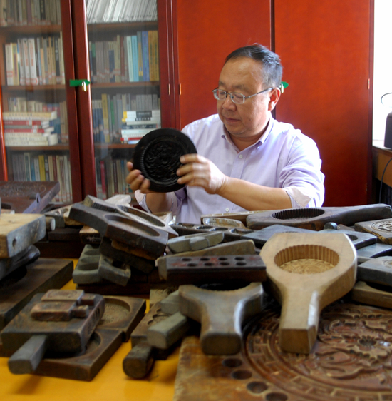 王来华和他所收藏的部分月饼模子。（受访者供图）