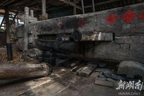 古法榨油 木槽里包裹着油料饼，用横向的木楔挤紧