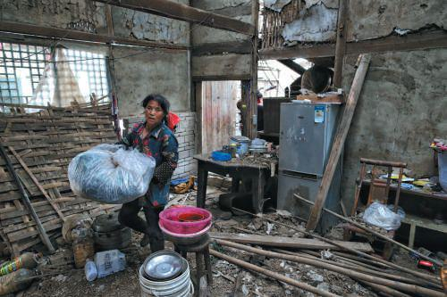 　▲昨日，双河镇，村民在破损的房间内整理物品，带走离开。