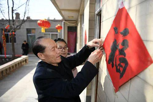 2020年1月24日，大年除夕，谢兴昌（前）与孙女一起贴福字。新华社记者王鹏摄