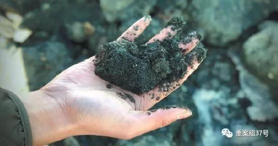 尾矿库用来筑坝的矿渣掉落在河道中，呈现蓝黑色，伴有异味。 新京报记者 游天燚 摄