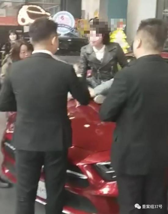  ▲女车主情绪激动地坐上奔驰车前盖与销售人员理论。受访者供图