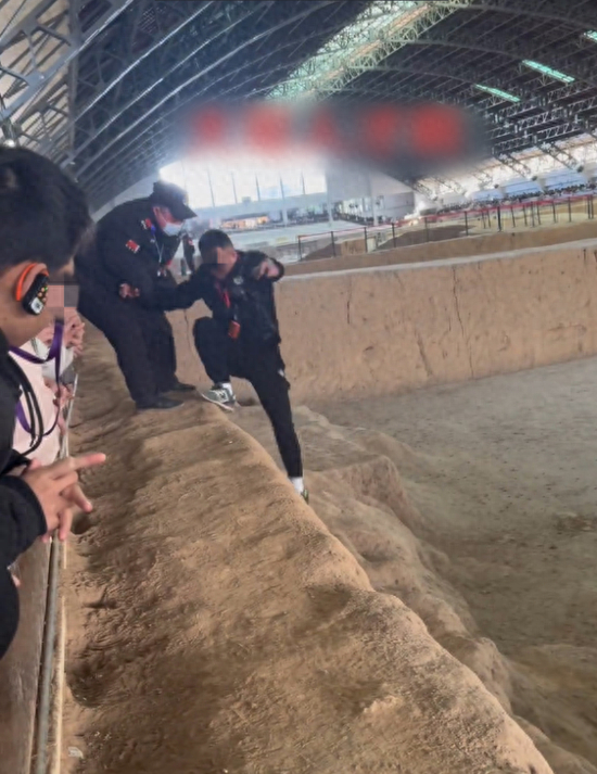 身着警服的工作人员将男子从兵马俑坑中拉出