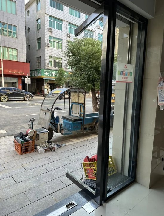 曾一芬店里的玻璃门被洪水冲碎只剩下门框。摄影/王仲昀