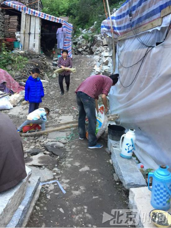 小廖（右一）在帮助村民搬东西。北京时间记者杨安平摄