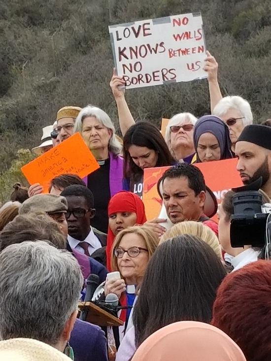 （支持移民的民众在边境地带举行示威，呼吁“爱无边界”傅毓涛摄。）