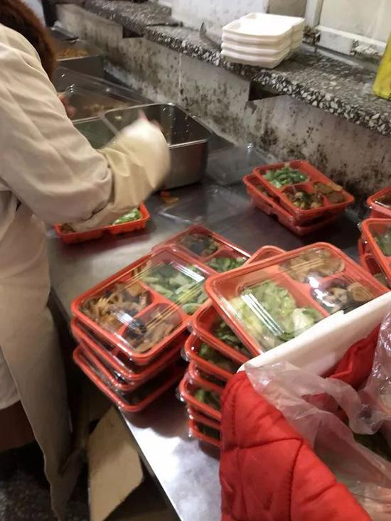 ▷饭菜在另一个操作台上被分装入盒