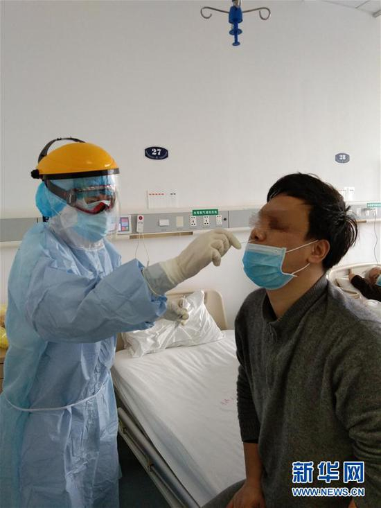 2月12日，在武汉大学人民医院东院区，四川大学华西医院的护士谢泽荣（左）给患者采集咽拭子样本。 新华社发