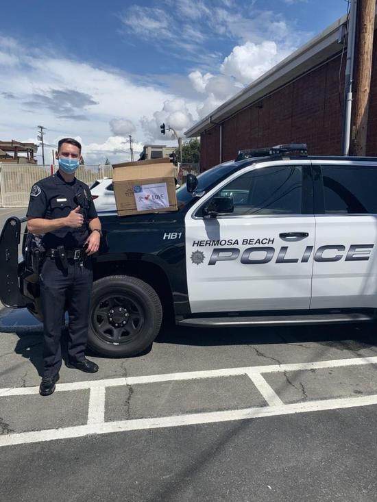 4月8日，在美国洛杉矶县赫莫萨比奇市，一名警察戴上华侨华人捐赠的口罩后留影。（新华社发，赫莫萨比奇市警察局供图）