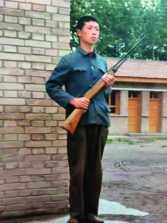 ·15岁时，祁发宝端着木枪在教室前模仿军人“站岗”。
