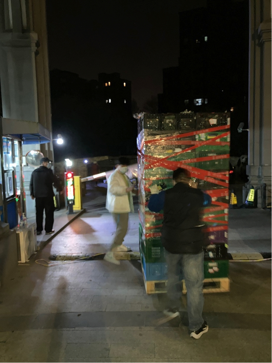  深夜里，陈延山（黑衣者）推着液压车爬坡，为社区运送生活物资。（受访者提供）