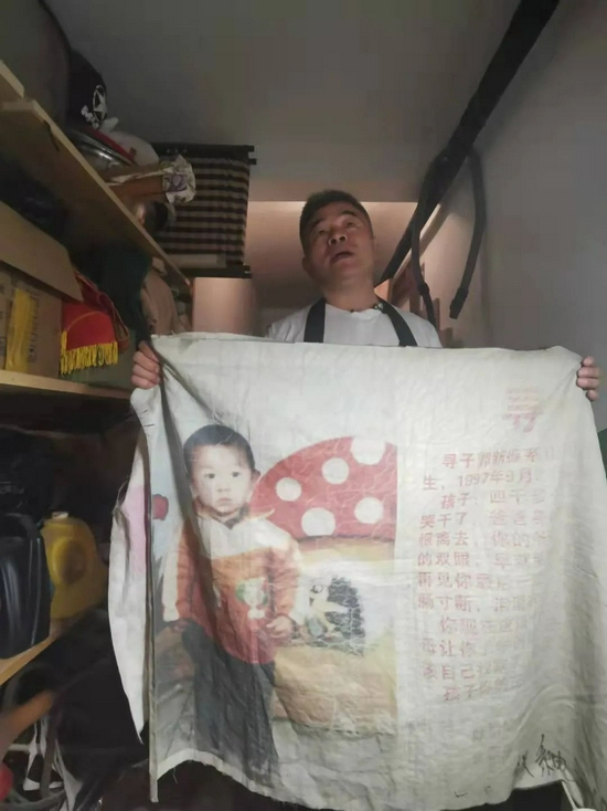 ▲9月11日，李太屯小区，郭刚堂展示他曾经插在摩托车上的寻人旗子。新京报 汪畅 摄