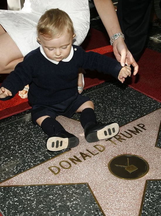 ·年幼的巴伦坐在刻有特朗普名字的星光大道上。