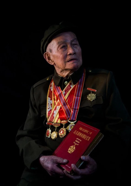 手捧《中国人民志愿军二十军抗美援朝英模纪念集》（1953）的文老英雄 &nbsp;杨建新摄