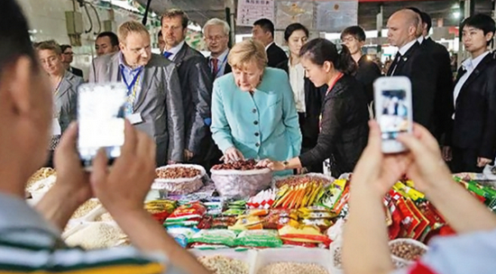  ·2014年7月6日，默克尔来到成都一处菜市场走访，她还买了一袋郫县豆瓣酱。