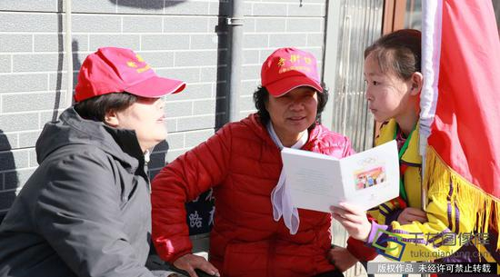 电厂路小学《小小冬奥组委》“学雷锋”志愿服务冬奥宣讲团向居民赠送学校印刷的《冬奥有我 知识读本》。学校供图。