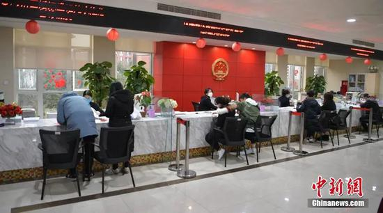  2020年2月14日，婚姻登记大厅窗口，新人正在办理结婚证。中新社记者 刘忠俊 摄