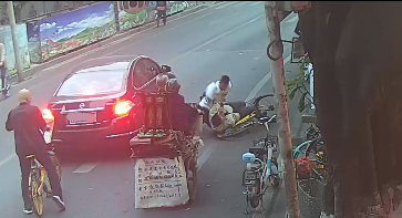 ▲唐某从自行车上跌倒，脚勾住了车轮，唐某用嘴咬住黄某的左手，黄某用手拍打唐某脸部。