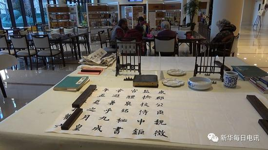 除夕前夕北京恭和家园展示老人墨宝，远处老人们共同制作春节礼物。邰思聪 摄