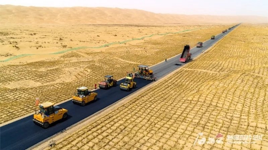 　　2021年4月27日，新疆第三条沙漠公路（尉犁至且末沙漠公路）铺油作业现场，工人们顶着高温加紧铺设沥青。石榴云/新疆日报记者韩亮、通讯员刘俊摄