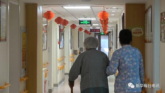 华方养老照料中心内护理员陪同老人散步。马晓冬 摄