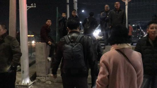 黑车司机挤在潞城地铁站A口对面停车场入口招揽生意。