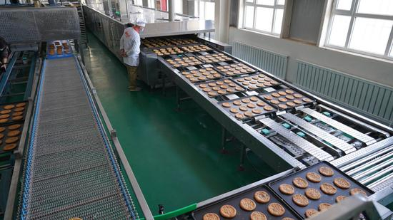 在新疆柯坪县玉尔其乡托玛艾日克村馕产业园里，工人在检查生产流水线（2020年11月4日摄）。新华社发