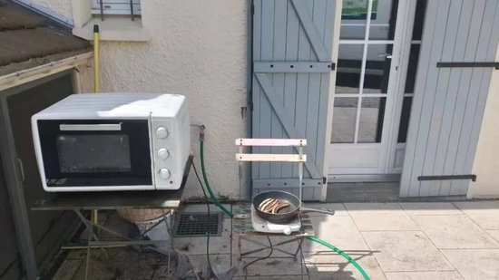  △当地人把电磁炉和烤箱放到院子里做饭。受访者供图