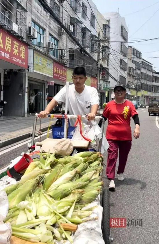 李庆章成推着推车卖玉米，奶奶陈恒福一路陪伴。（极目新闻记者 黄志刚 摄）