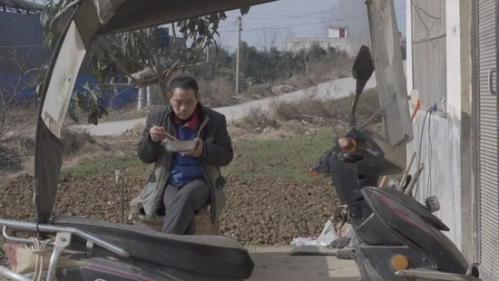 12月14日，王中明坐在门口吃饭。新京报记者 戚厚磊 摄