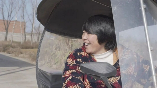 12月14日，韩仕梅骑着电动车外出和村里人打招呼，韩仕梅表示，写诗后村里人对她热情了很多。新京报记者 戚厚磊 摄