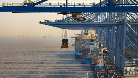 △上港集箱外高桥码头，巨型塔吊正在吊装集装箱货柜。（总台国广记者李晋拍摄）