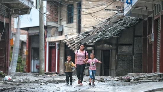 　▲昨日，四川省长宁县双河镇，一位母亲领着两个孩子准备去临时安置点休息。 新京报记者 彭子洋 摄&nbsp;