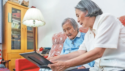 六月二十三日，在北京的家中，瞿独伊（左）和女儿李晓云向记者展示家人的相册。新华社记者 才 扬摄