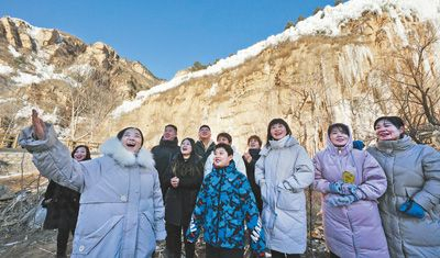 冬日清晨，河北阜平县龙泉关镇骆驼湾村迎来日出，村民在为游客讲解太行山独特的“日照冰瀑”景观。本报记者 李 舸摄