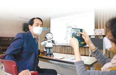 2020年11月16日，在韩国首尔阳川区一处老年福利文化中心，一名老人和教学机器人在学习结束后合影留念。新华社记者 王婧嫱摄