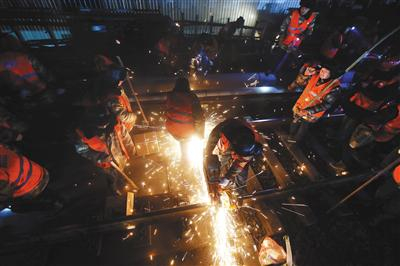 昨日凌晨，工人用电锯切割钢轨，锯齿和钢轨不断摩擦出明亮的火花。本版摄影/新京报记者 王贵彬