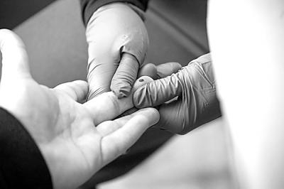 在美国纽约布鲁克林区一家超市内的新冠抗体检测点，工作人员采集被测者血样。