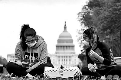 在美国首都华盛顿，两名戴口罩的女子坐在国家广场草坪上。新华社发